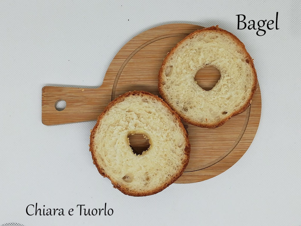 Un Bagel tagliato a meta' e posato su un piccolo vassoio di legno