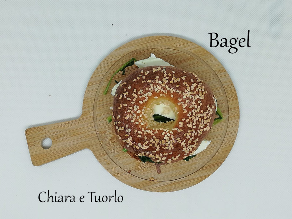 Bagel farcito, posato su un piccolo vassoio di legno, inquadrato dall'alto