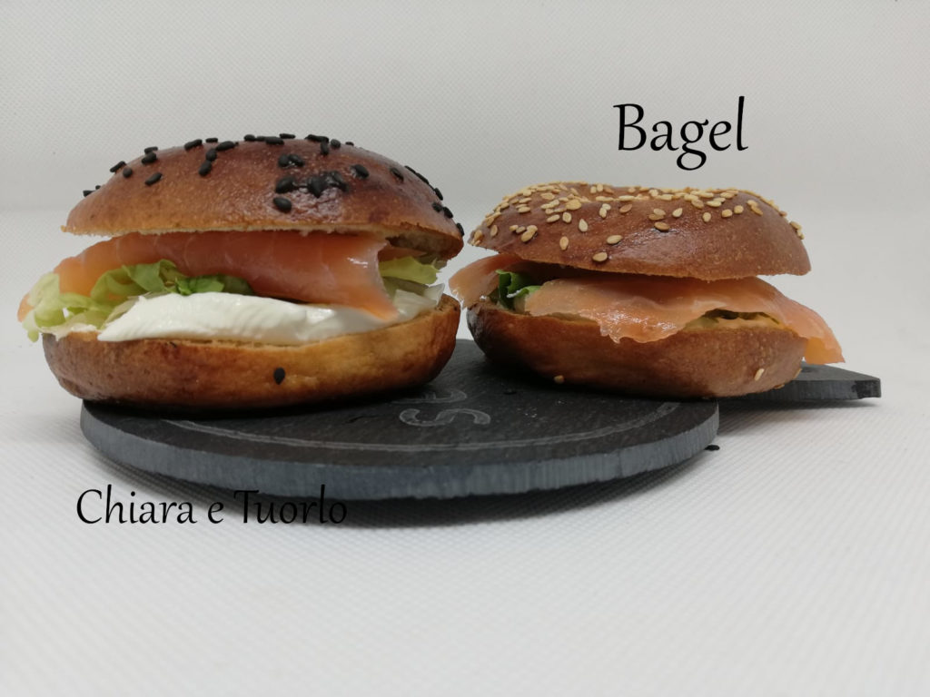 Due bagel su un vassoio, farciti con formaggio spalmabile, insalata e salmone affumicato