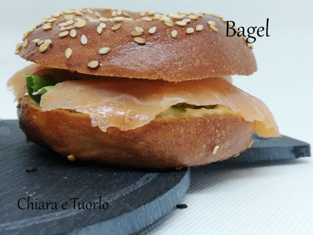 Un bagel su un vassoio, farcito con formaggio spalmabile, insalata e salmone affumicato