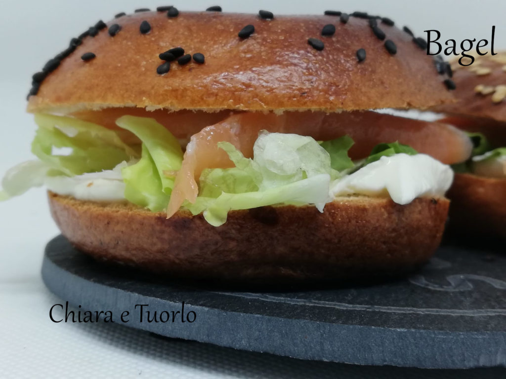 Primo piano di un bagel farcito con formaggio spalmabile, insalata e salmone affumicato