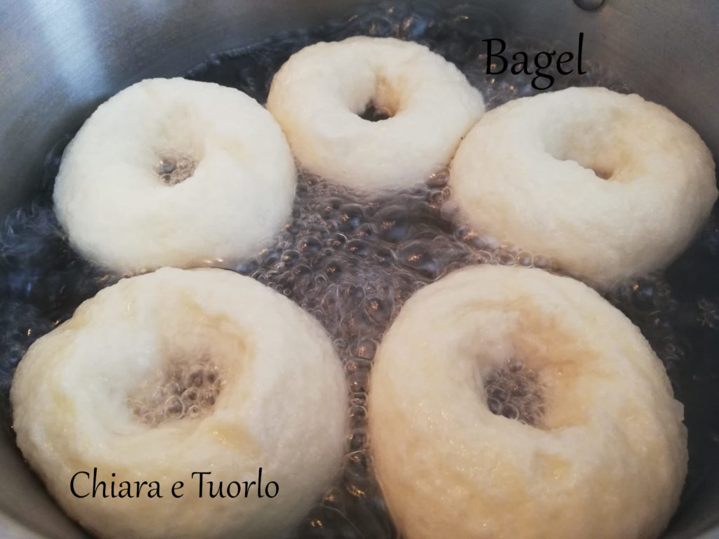 Bagel in fase di bollitura, in pentola con acqua e zucchero