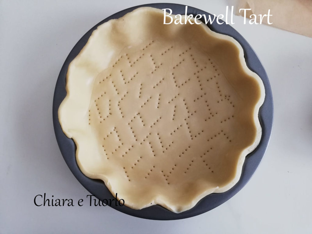 Bakewell Tart stesa nella tortiera e con il fondo forato dalla forchetta.