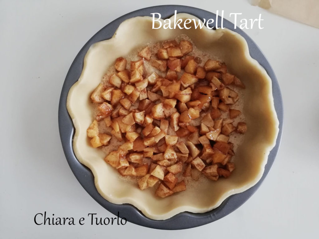 Bakewell Tart stesa nella tortiera e con il fondo cosparso di pangrattato e composta di mele