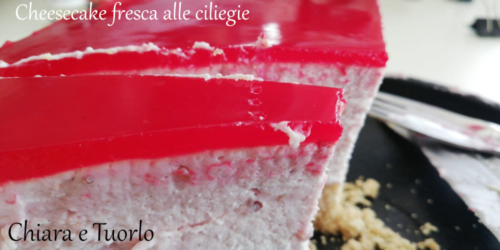 Fetta di Cheesecake fresca alle ciliegie, inquadrata dal fianco e con la glassa rossa in evidenza