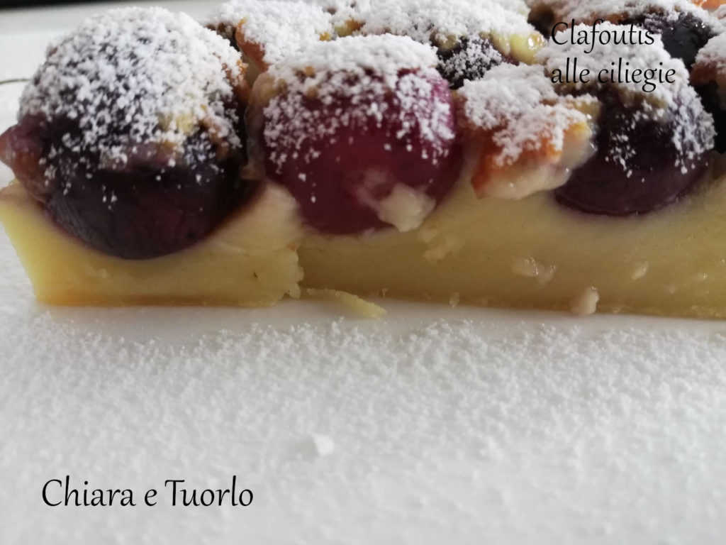 particolare di fetta di Clafoutis cotta e spolverata di zucchero a velo inquadrata da lato