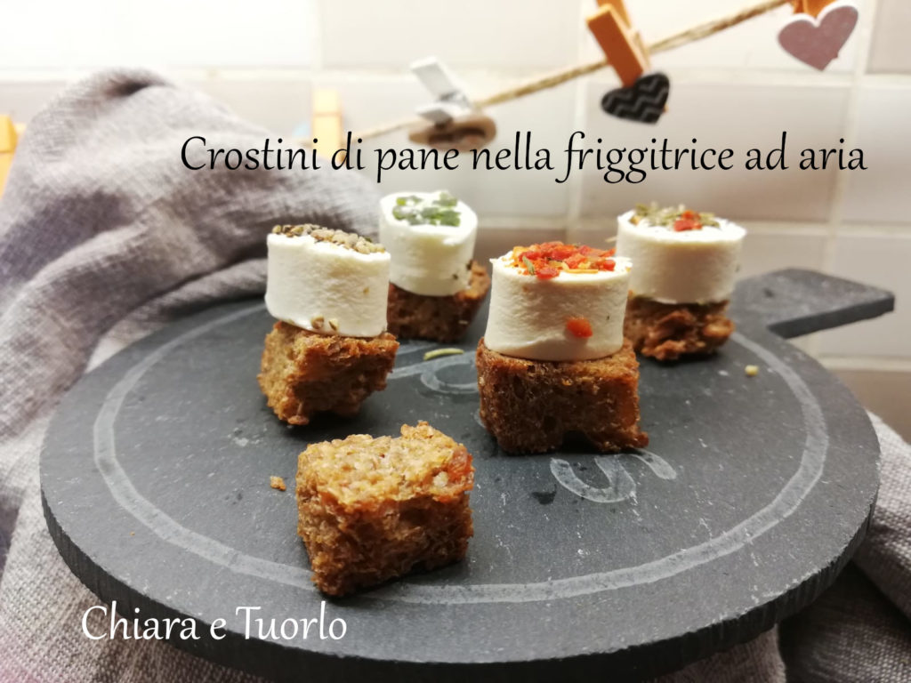 Crostini di pane preparati nella friggitrice ad aria con formaggi freschi, su un vassoio di ardesia