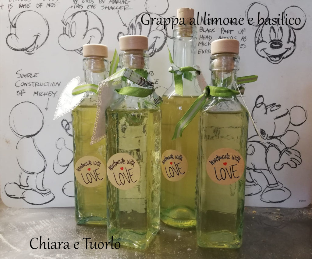 Quattro bottiglie di vetro riempite della grappa al limone e basilico
