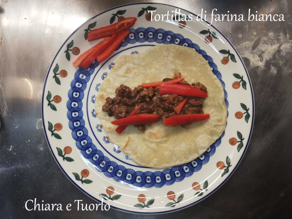 Tortilla appoggiata su un piatto, farcita con chili e peperone