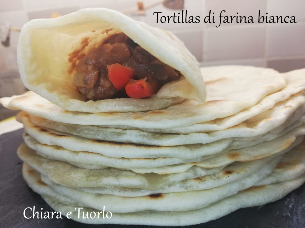 Tortilla farcita e arrotolata, appoggiata su una pila di altre Tortillas