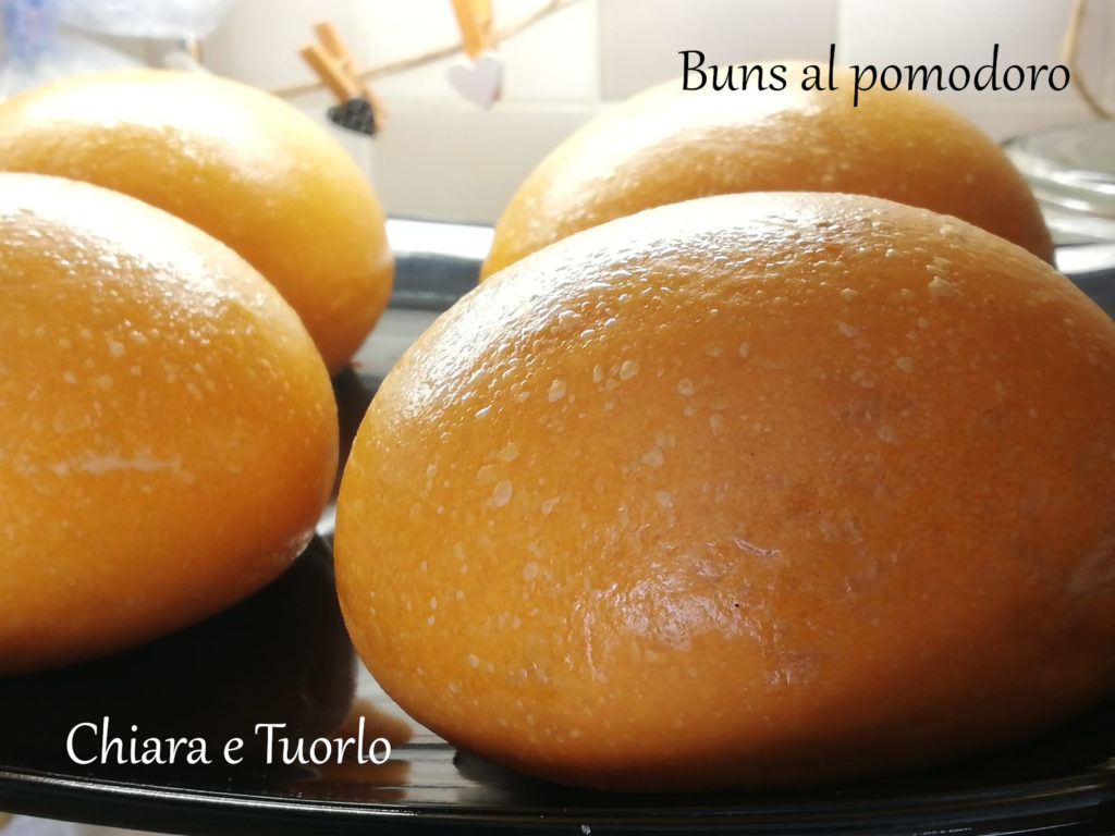 quattro buns al pomodoro inquadrati di lato, di colore arancione e perfettamente lucidi e tondeggianti