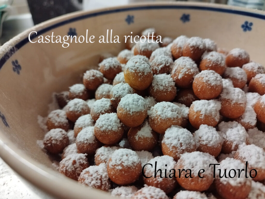 Una terrina piena di castagnole alla ricotta con abbondante zucchero a velo sopra