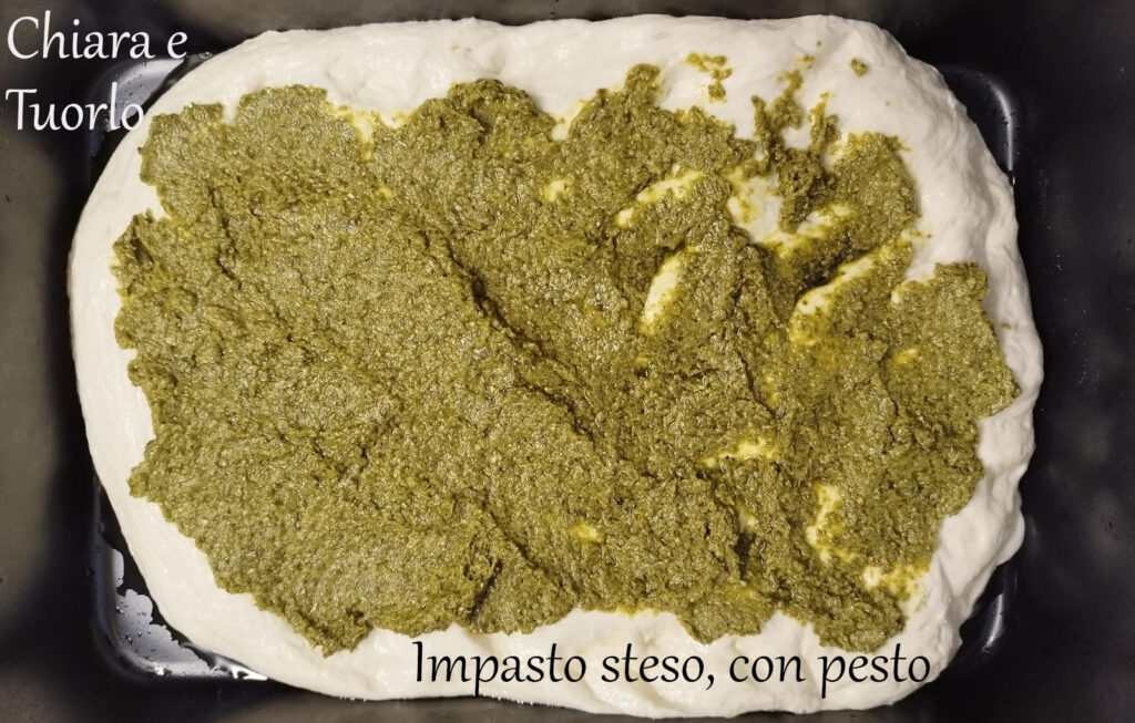 Impasto steso in teglia e cosparso con il pesto
